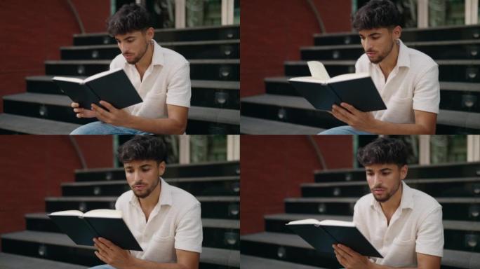 年轻的阿拉伯男子坐在街上的楼梯上读书