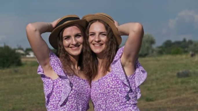 肖像两个年轻的双胞胎女孩穿着相同的衣服在大自然中看着相机