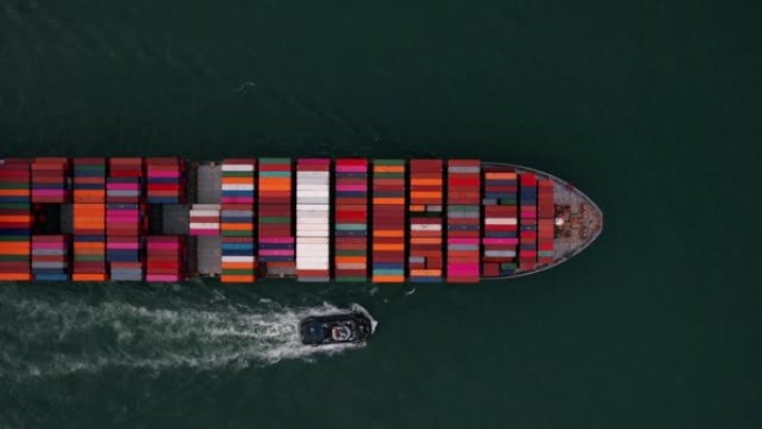 Aerial top view cargo container ship with contrail