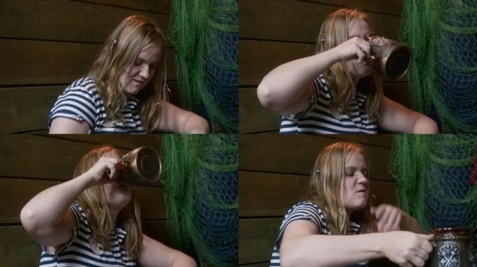 粗鲁的年轻水手女子带着肮脏的脸从一个大的陶瓷杯里喝，把它放在桌子上，打嗝，随便用手擦擦她的嘴，挥动某