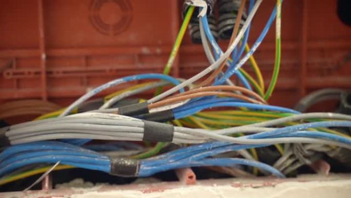施工现场接线盒内安装的肮脏彩色电缆的特写镜头。家中绞合高压电缆绝缘，电线布置正常运行。维护电力，工程