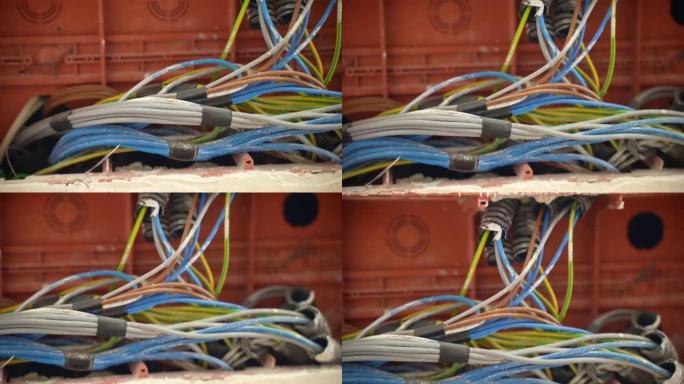 施工现场接线盒内安装的肮脏彩色电缆的特写镜头。家中绞合高压电缆绝缘，电线布置正常运行。维护电力，工程