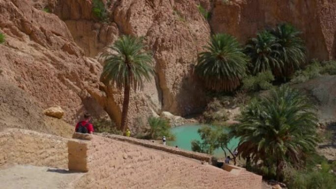 背着背包的徒步旅行者走下楼梯到沙漠中的小湖。