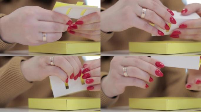 一个面目全非的女人折叠了一个黄色的小纸箱。用纸生产纸板箱。包装制造公司。在创意课上做纸工艺品的手的特