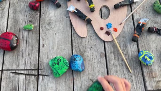 一个孩子玩涂有丙烯酸涂料的鹅卵石。石头上的艺术品。
