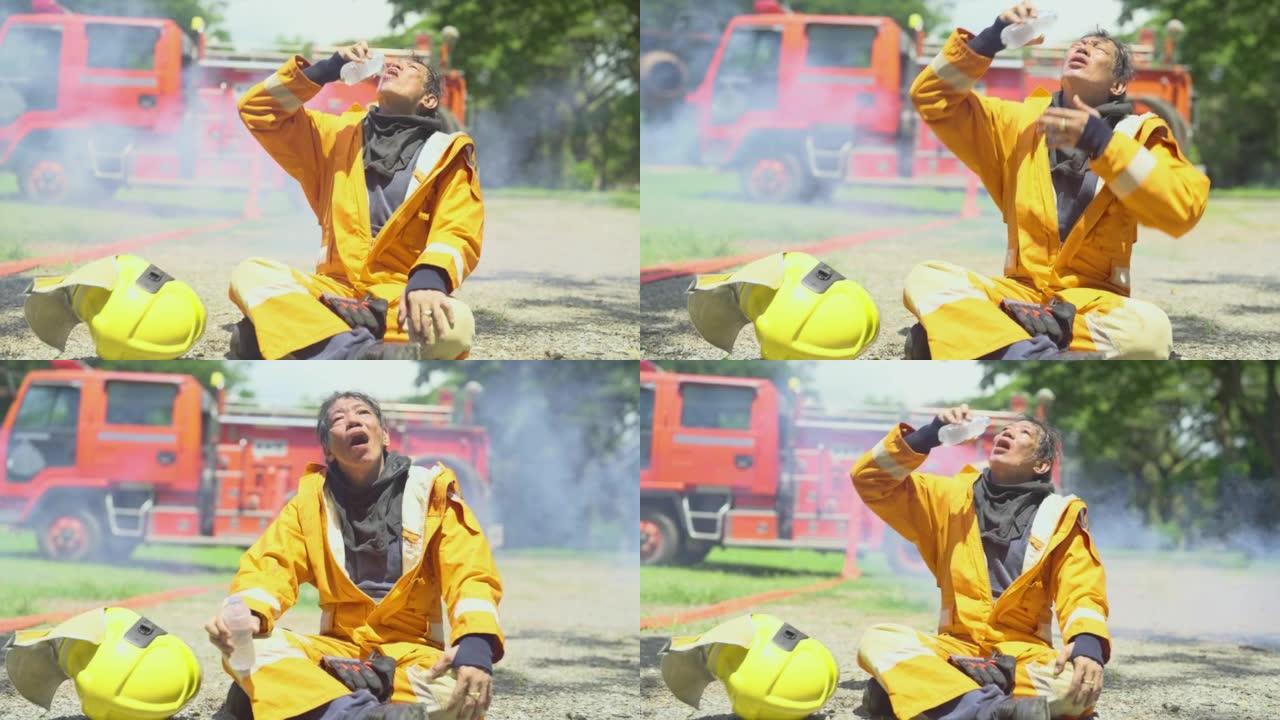 消防员坐在消防车或消防车前，用水倒在他的脸和嘴上，看起来他完成并成功区分火
