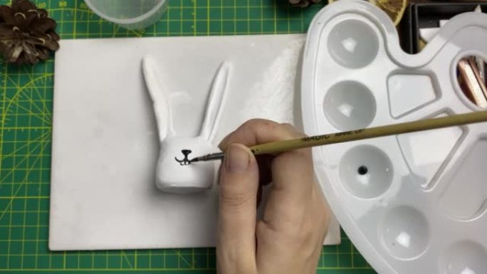女艺术家在粘土兔子上用刷子画枪口。
