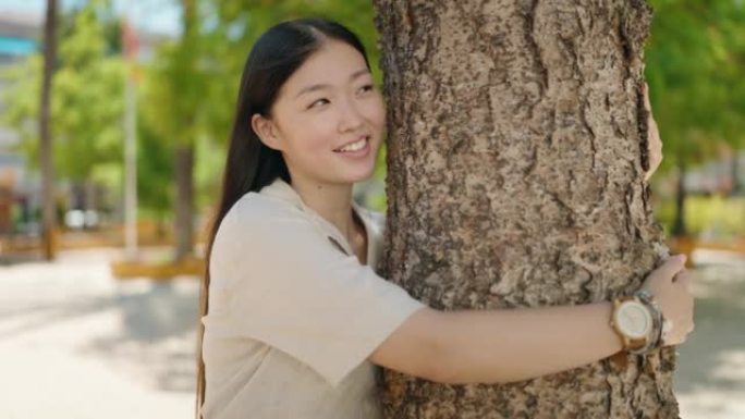 中国女人在公园里微笑着自信的拥抱树