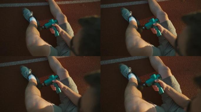 运动男性用手按摩枪按摩肌肉，从体育场跑步锻炼中恢复过来。。训练后手持无线专业振动休克按摩器进行身体治