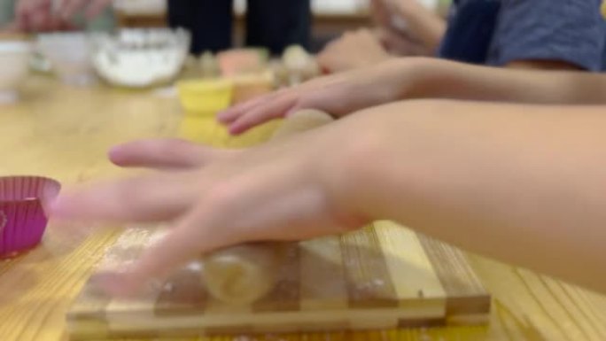 使用木制rolling面杖准备馅饼面团的小孩的特写镜头
