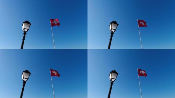 瑞士国旗，前面是旧灯。瑞士国旗在风中挥舞，背景中仿古油灯在风中挥舞