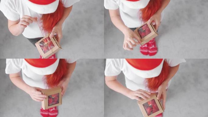 一个女孩从牛皮纸礼品盒中收到并打开包装，并在圣诞节和新年装饰的白色背景上用红色蝴蝶结打开包装。一个红