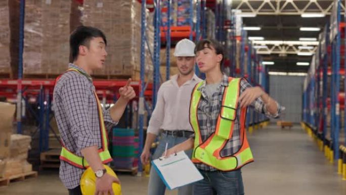 仓库人员小组检查生产存储。在一个巨大的工业仓库中，穿着安全制服和安全帽的多民族工业同事讨论了分配计划