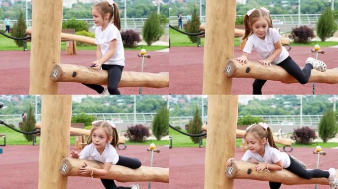 一个有两条尾巴的快乐小女孩坐在一根大木头上，快乐地在一个有障碍的现代运动场上玩耍