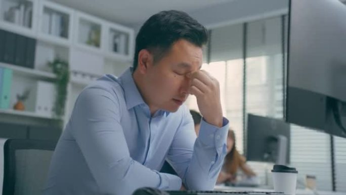 亚洲年轻沮丧的商人深夜办公室工作。有吸引力的英俊男性员工使用笔记本电脑在线交流互联网聊天以完成紧急工