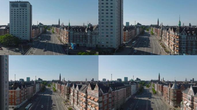 市区宽直街道的鸟瞰图。在联排别墅衬砌的主干道上，交通流量低。背景中的高塔。丹麦哥本哈根