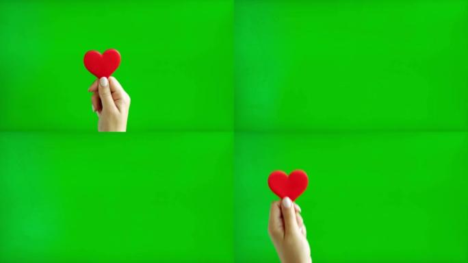 米色修指甲的女性手握着红色的心，孤立在绿色屏幕背景上。特写。色度键屏幕上红心的人手特写。喜欢。4k镜