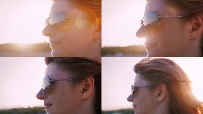 日落时海滩上一个快乐自由女人的特写镜头，头发随风飘扬，侧视图，夏日