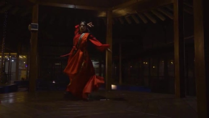 中国妇女在棕色凉亭内穿着红色传统的中国服装跳舞