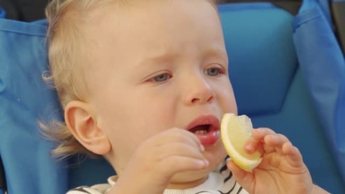 男婴第一次吃柠檬，拉傻脸。有趣的孩子第一次尝试柠檬。