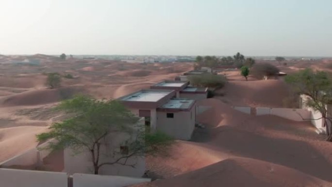 无人机飞越沙漠中被沙子覆盖的阿拉伯房屋