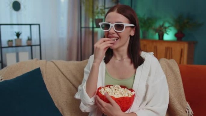 女人坐在沙发上吃爆米花，在家看有趣的电视连续剧，在线体育游戏