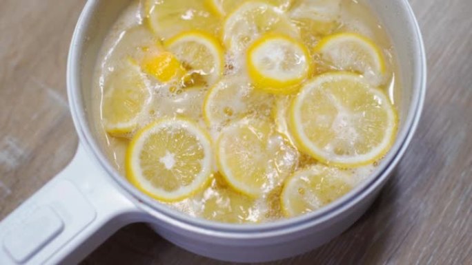 4k镜头在电锅中用沸腾的糖浆煮柠檬，用于制作蜂蜜柠檬苏打