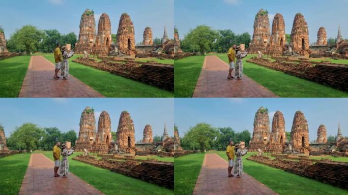 泰国大城府 (Ayutthaya) 在Wat Mahathat，一对男女戴着帽子和旅游地图参观泰国大