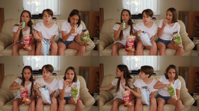 青少年姐妹女孩三胞胎有趣的坐着吃脆薯片扔和用嘴抓