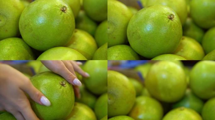 女人的手从架子上拿柚子水果。超市中的有机食品