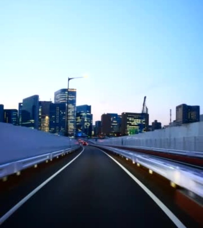 黄昏时开车穿过城市。过桥。