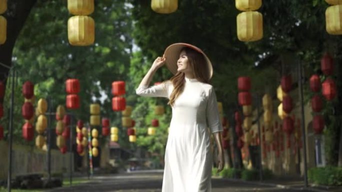 穿着传统服装和亚洲风格圆锥形帽子的4k越南女人在街上挂着传统的中国灯笼
