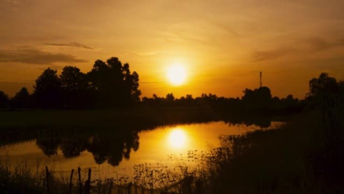 太阳在稻田里慢慢升起。泰国日出时间流逝，感觉非常温暖。希望符号。四周轮廓优美。