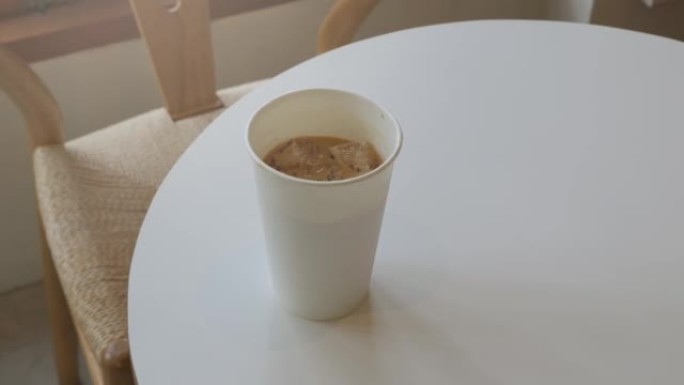 在白色桌子上拿一杯冰牛奶咖啡拿铁，在纸杯里拿卡布奇诺冰咖啡