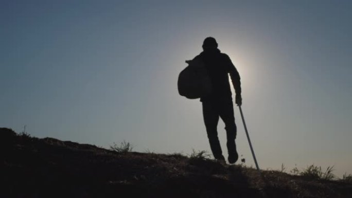活跃的人使用登山杖在日落时爬上山坡