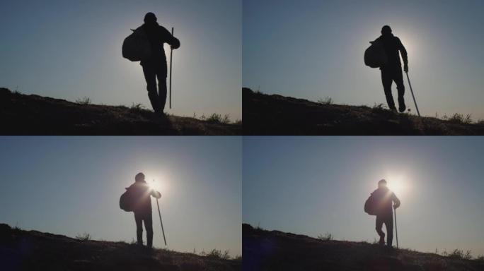 活跃的人使用登山杖在日落时爬上山坡