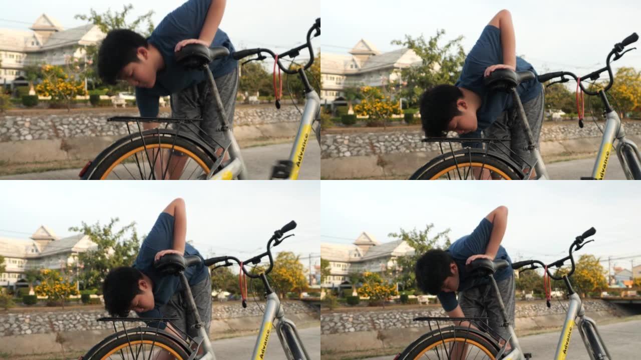 亚洲少年男孩修理自行车链条，当它在户外抛锚时。