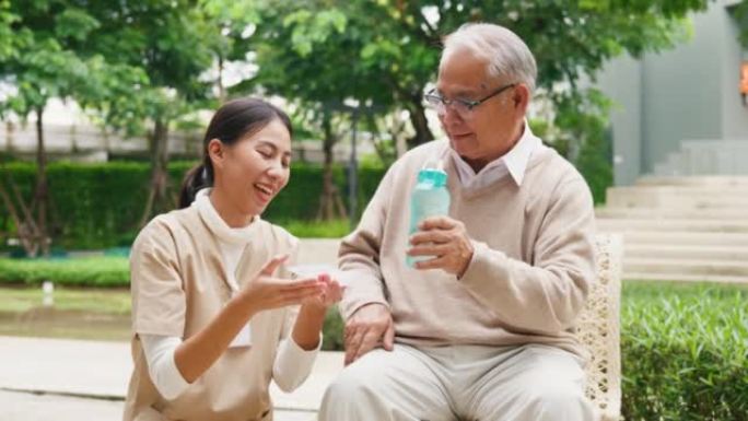 年轻的亚洲女性照顾者，老人照顾者，老人在公园，服药后喝水，退休后治愈或治疗老年人的疾病，帮助支持。