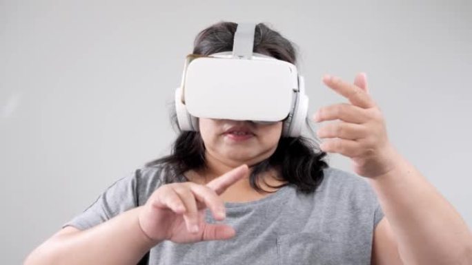 大型构建亚洲成年女性在灰色背景下使用虚拟现实，技术生活方式概念。