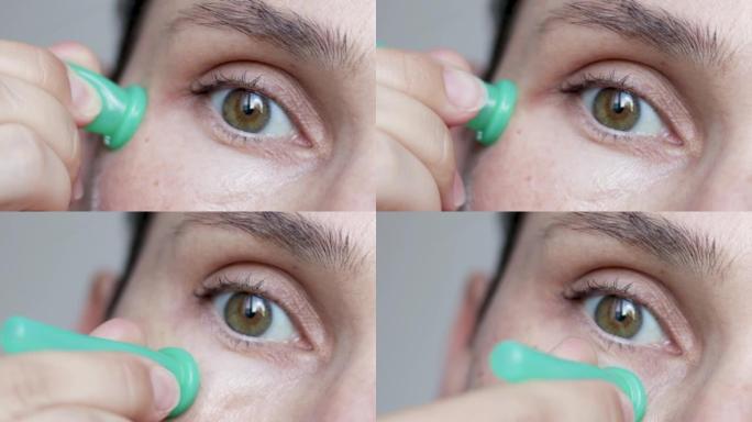 用绿色真空硅胶杯做面部拔罐的女人。去除眼袋下的浮肿。特写女性眼部抗衰老抗皱