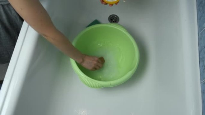 女人正在盆中准备水洗衣服，倒入洗衣粉。