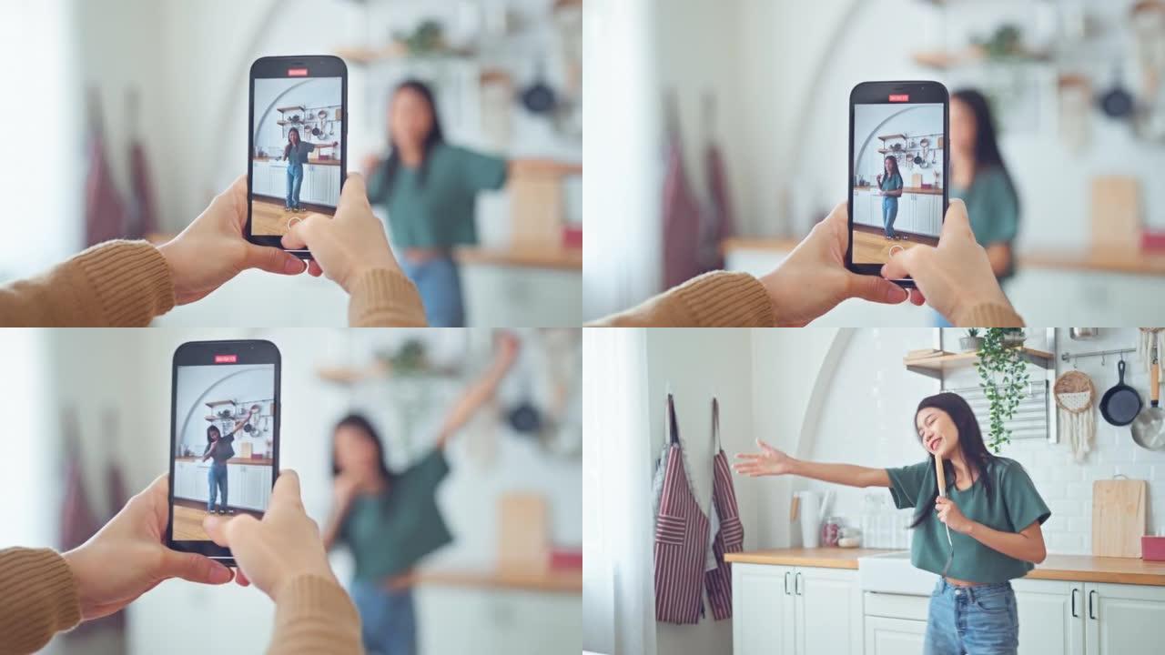 用智能手机拍摄亚洲快乐女人的手在为社交媒体，故事和vlog概念制作视频时在家跳舞。