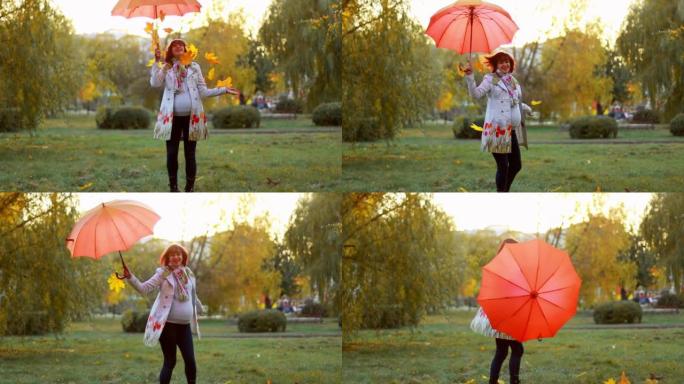 怀孕的白人女孩穿着雨衣，带伞，在日落时扔下秋天的枫叶橙叶。秋。等待孩子的出生。女人在自己周围旋转。幸
