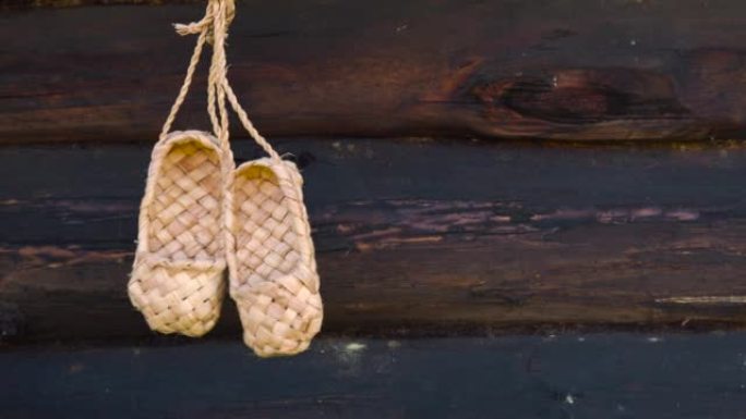 古董手工乡村鞋-韧皮鞋。一双挂在木木墙背景上的韧皮鞋。