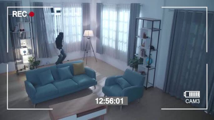 监视器的屏幕记录了一个小偷拿着手电筒打开窗户并在走路前进入某人的房子