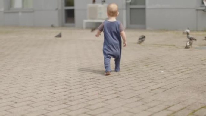 赤脚男婴在灰色的人行道上学习走路