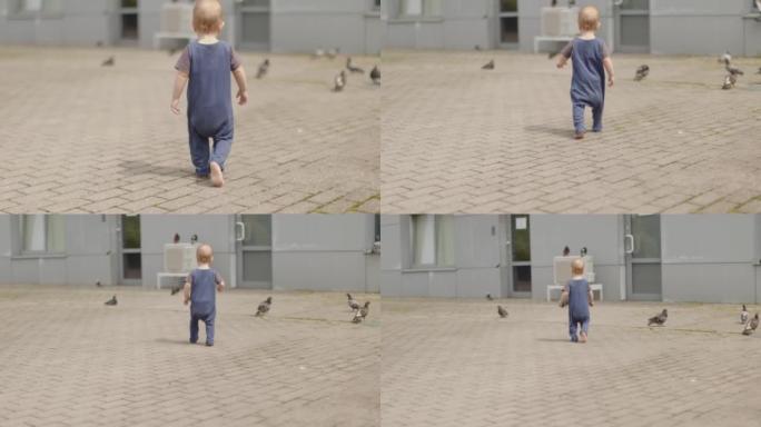 赤脚男婴在灰色的人行道上学习走路