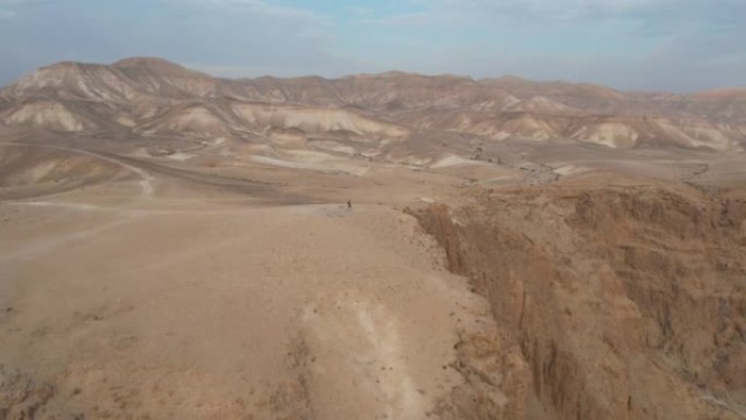 在沙漠景观中的悬崖上行走的人。