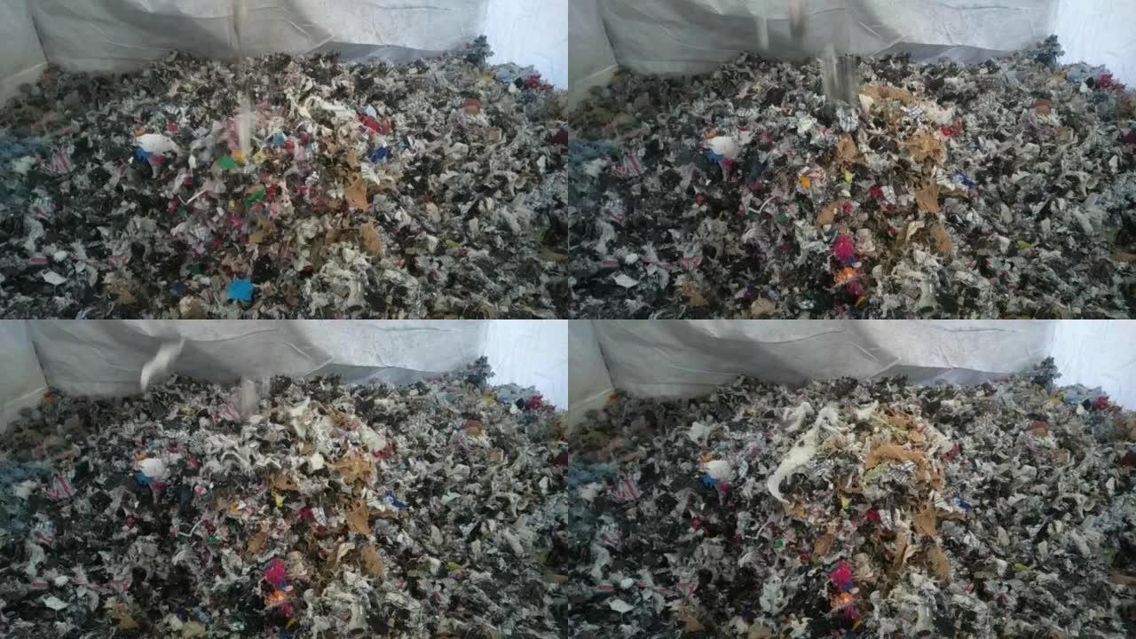 粉碎掉的纺织品废料落到一个大袋子里。30fps概念回收行业。特写