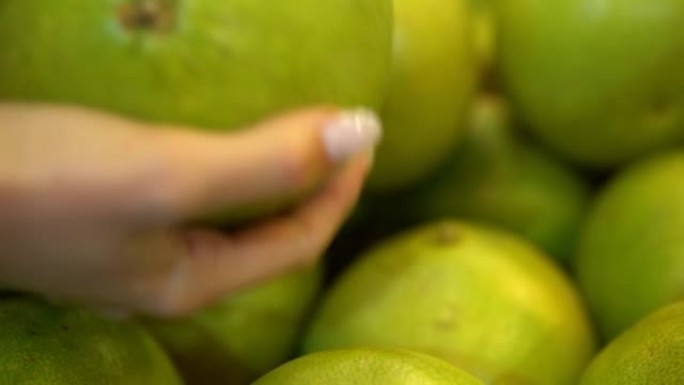 手拿绿色柚子水果。女人在超市买食物